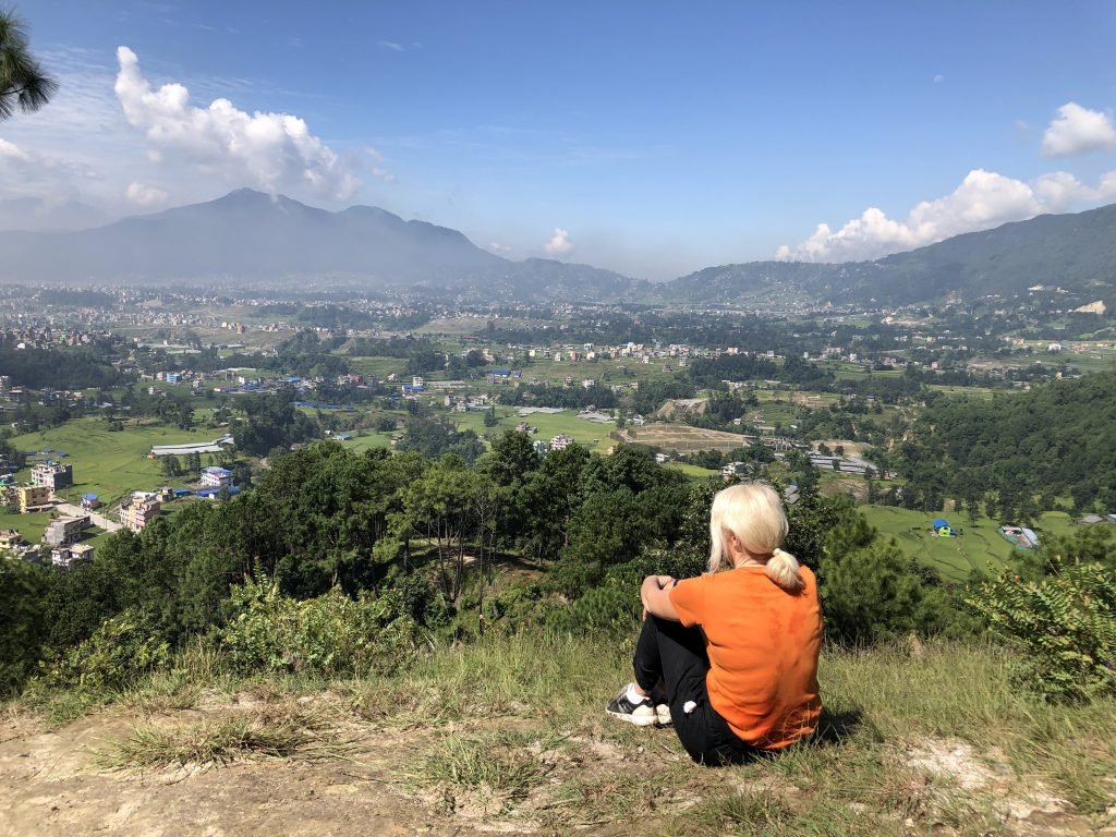 Jayne sitting on top of a hill on her Nepal Trip