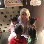 Jayne smiling, surrounded by school children whilst volunteering in Nepal