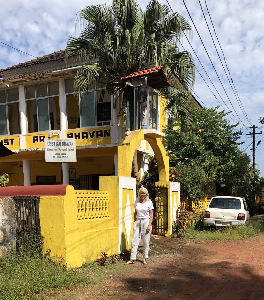 Jayne standing outside old aged home on one of her projects for volunteers