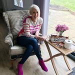 Jayne sitting in chair smiling ready to write midlife crisis blog